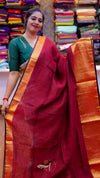 Woman wearing a red saree with a green blouse in a fabric store.