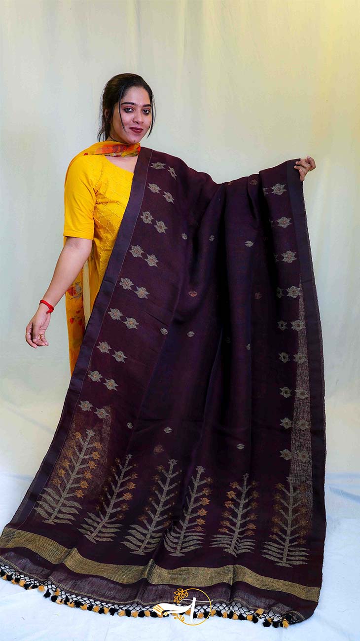 Woman holding a dark brown saree with leaf patterns on a white background