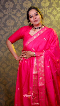 Woman wearing a bright pink saree with a decorative pattern against a patterned background