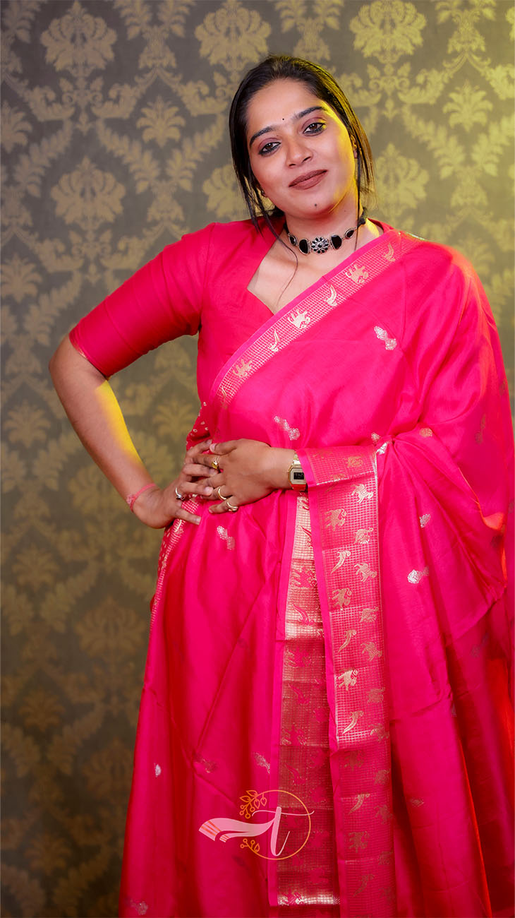 Woman wearing a bright pink saree with a decorative pattern against a patterned background