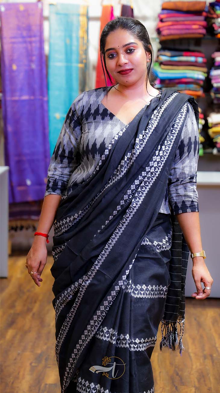 Woman wearing a black and white saree with a colorful fabric background