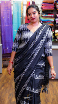 Woman wearing a black and white saree with a colorful fabric background