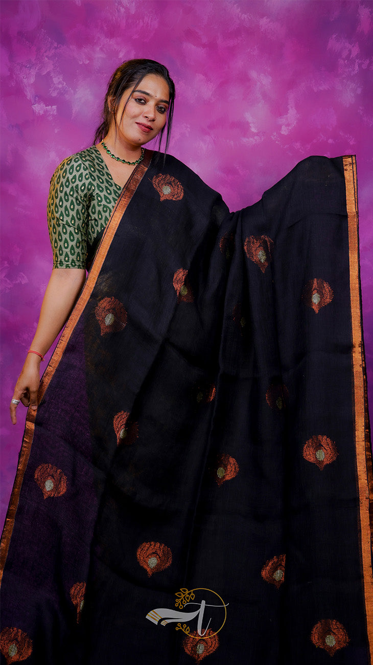 Woman wearing a black saree with gold patterns against a purple background