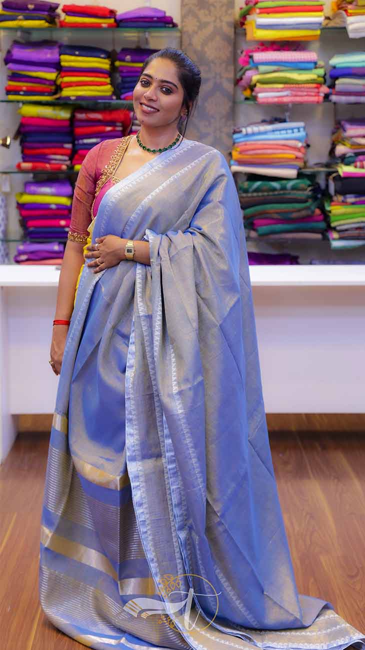 Woman wearing a blue saree with a background of colorful fabrics