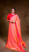Woman wearing a bright orange saree with a matching blouse against a brown background