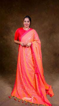 Woman wearing a bright orange saree with a matching blouse against a brown background