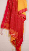 Red and yellow saree with white patterns on a light gray background