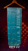 Teal fabric with geometric patterns on a hanger against a dark background