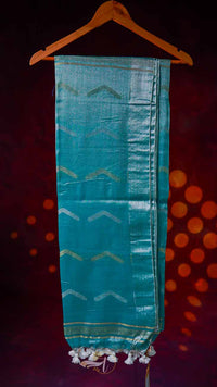Teal fabric with geometric patterns on a hanger against a dark background