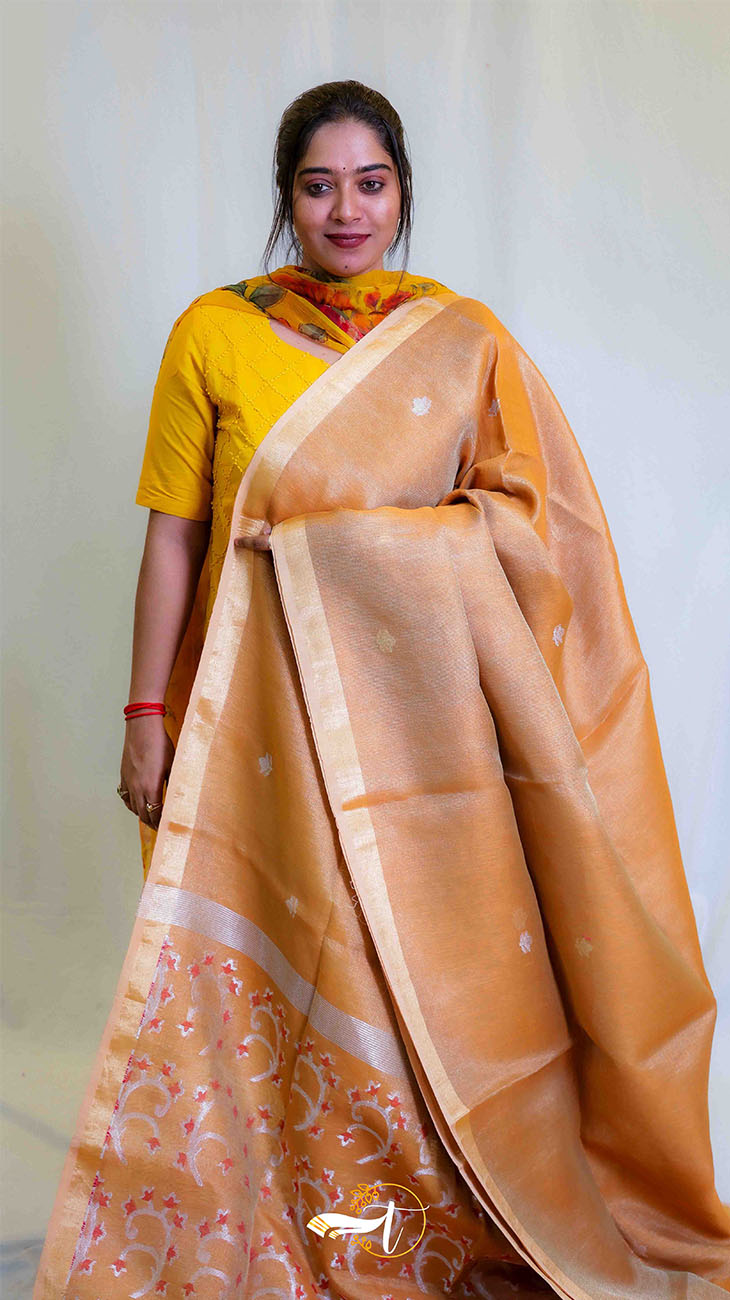 Woman wearing a yellow saree with a white blouse against a plain background
