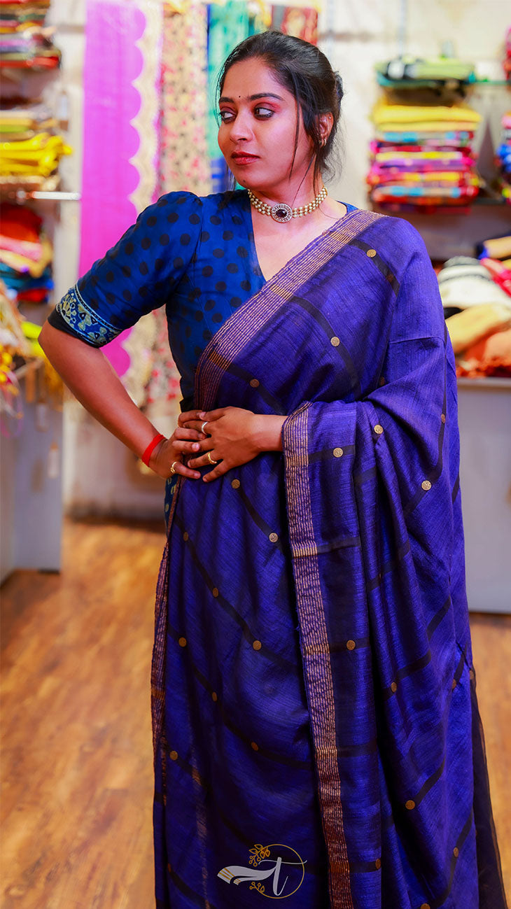 Woman wearing a blue saree with a traditional design in a store setting