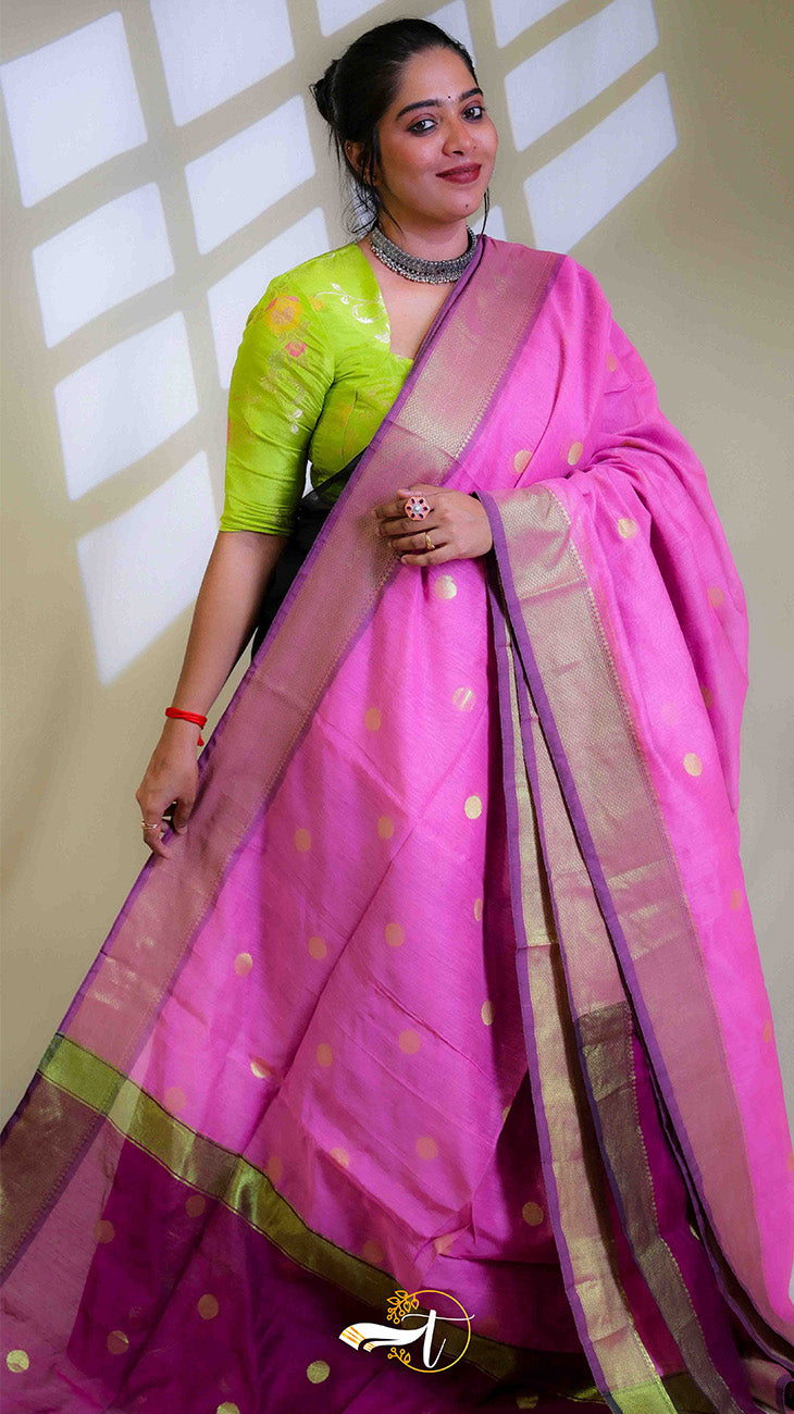 Woman wearing a pink saree with a green blouse against a neutral background