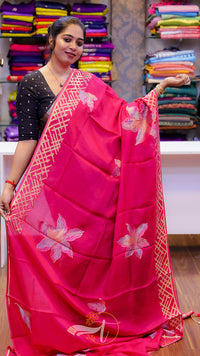 Woman wearing a pink saree with floral patterns in a store setting