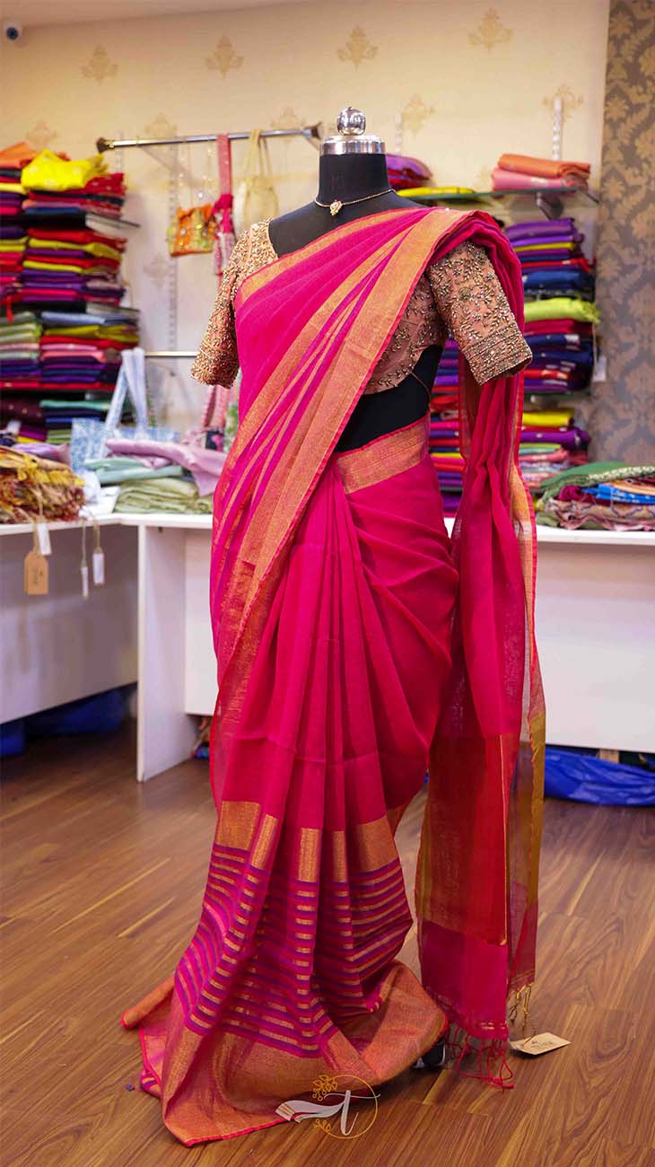 Pink saree with gold border on a mannequin in a store setting