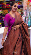 Woman wearing a brown saree with a purple blouse in a fabric store.