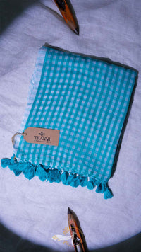 Turquoise checkered towel with tassels on a light gray background