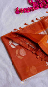 Orange fabric with floral patterns and tassels on a white background