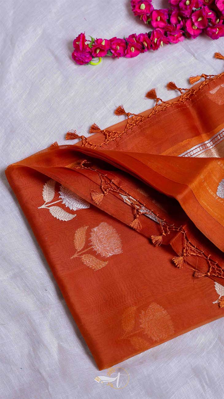 Orange fabric with floral patterns and tassels on a white background