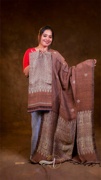 Woman holding a large brown and beige patterned fabric against a brown background