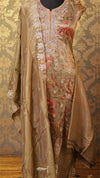 Traditional embroidered outfit with floral patterns on a textured wall background