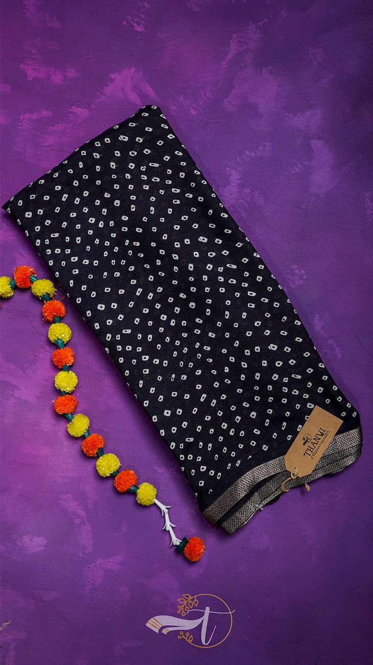 Black patterned fabric with colorful pom-pom trim on a purple background