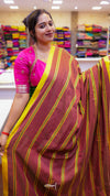 Woman wearing a pink and maroon saree with yellow stripes in a store setting.