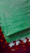 Green saree with white border and tassels on a red background