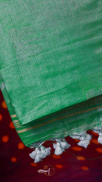 Green saree with white border and tassels on a red background