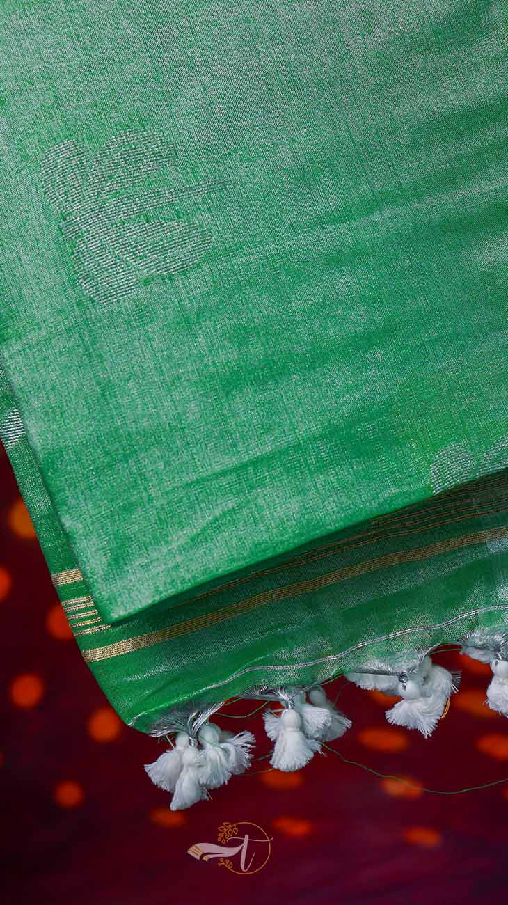 Green saree with white border and tassels on a red background