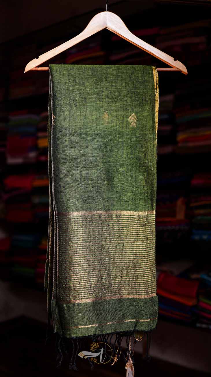 Green fabric with patterns on a hanger against a blurred background