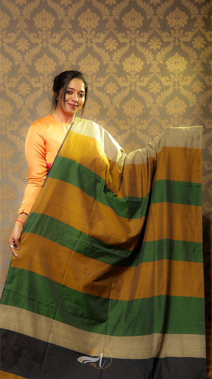 Woman holding a green and yellow saree against a patterned wall.