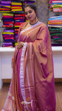 Woman wearing a pink saree with a blurred background of colorful fabrics