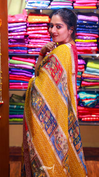 Woman in a colorful saree standing in front of a display of multicolored fabrics.