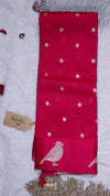 Red fabric with white polka dots and bird design on a textured surface