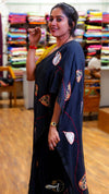 Woman wearing a black saree with colorful patterns in a store setting