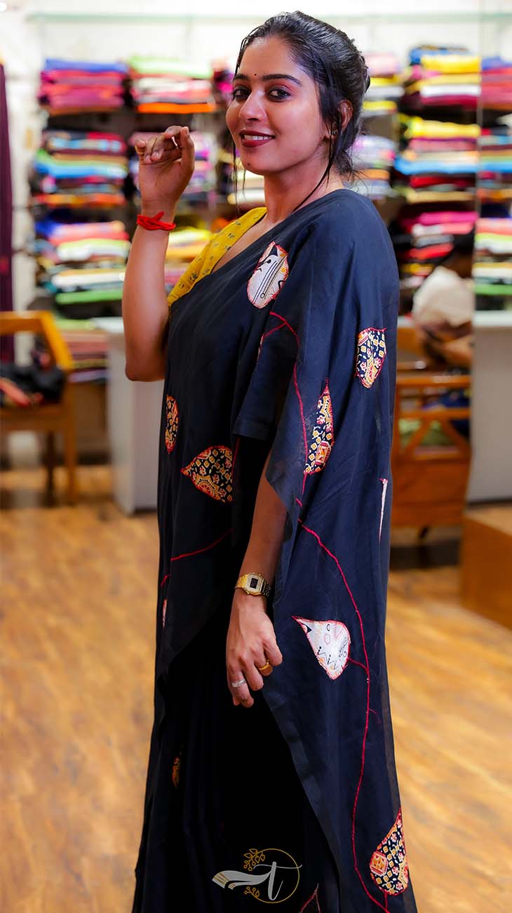 Woman wearing a black saree with colorful patterns in a store setting