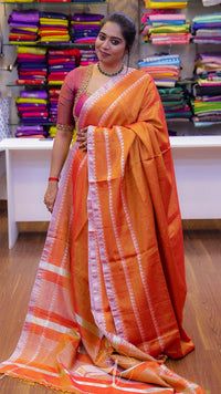 Woman wearing an orange saree with a striped pattern in a store setting.
