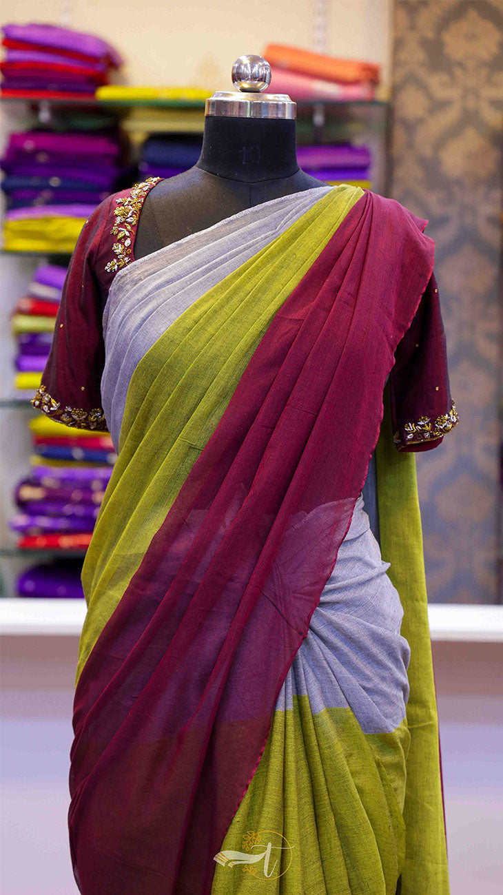 Saree with maroon and green colors on a mannequin against a colorful fabric background
