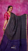 Woman holding a black and purple saree against a pink background
