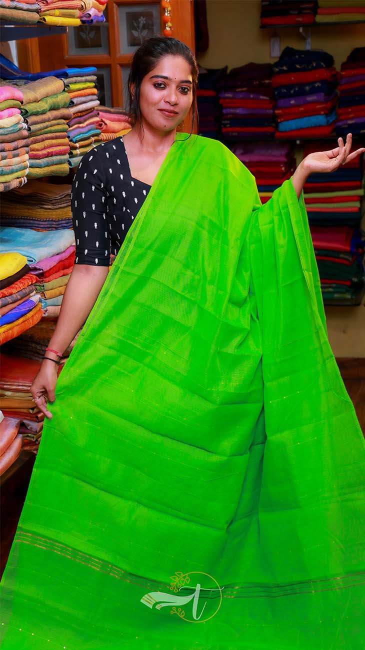 Woman wearing a bright green saree in a fabric store.