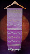 Purple fabric with white zigzag pattern on a wooden hanger against a dark background