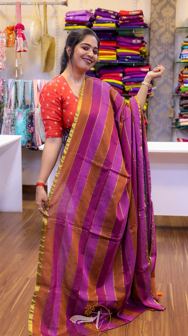 Woman holding a purple and orange saree in a store setting