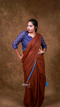 Woman wearing a brown saree with a blue blouse against a brown background
