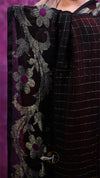 Close-up of a fabric with floral embroidery and a checkered pattern on a purple background