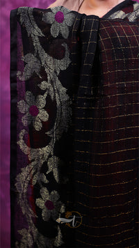 Close-up of a fabric with floral embroidery and a checkered pattern on a purple background