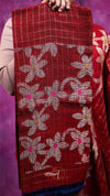Red fabric with floral patterns held by a person against a purple background