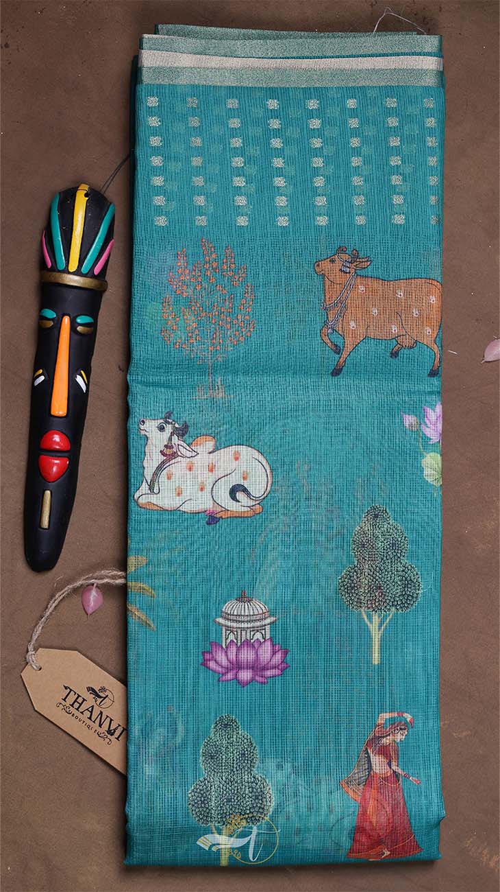 Turquoise fabric with animal and nature patterns, accompanied by a colorful pen and tag on a brown surface.