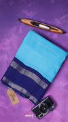Blue fabric with a brown tag and black camera on a purple background