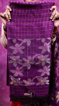 Purple fabric with floral patterns held by a person against a purple background
