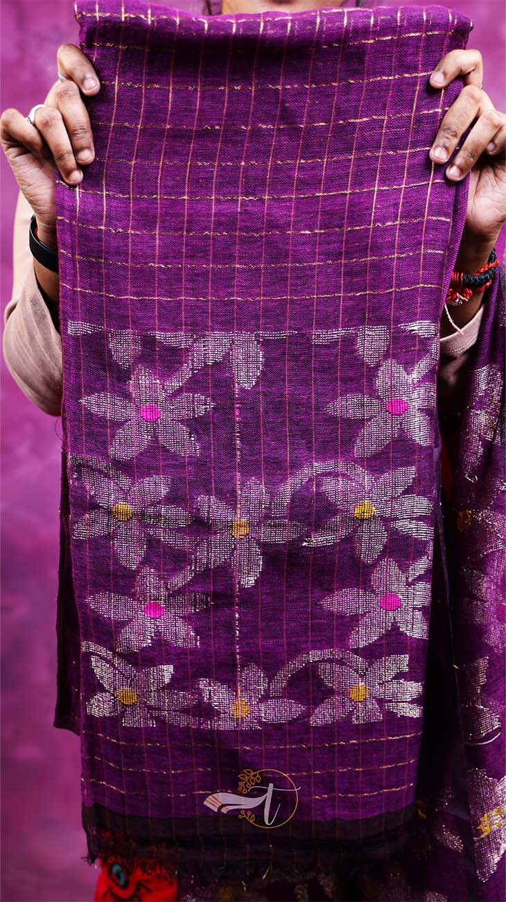 Purple fabric with floral patterns held by a person against a purple background